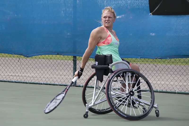 A woman using a sports wheelchair to play tennis
