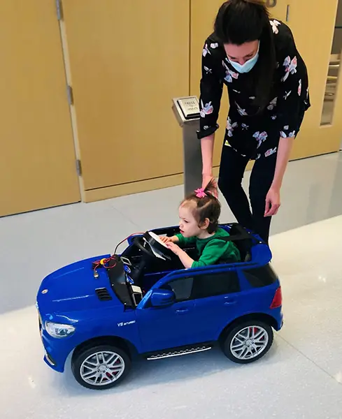 A parent helping their child steer the GoBabyGo car