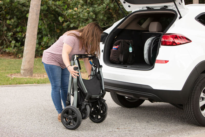 A woman folding a stroller to place it in her car