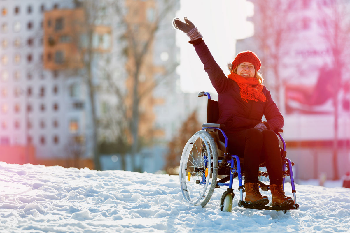 Nainen käyttämässä pyörätuolia lumisella maalla