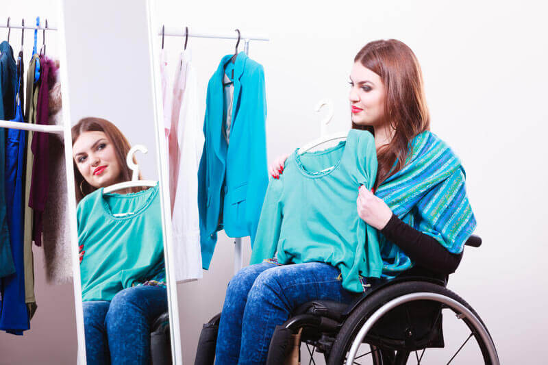 A woman using a wheelchair and deciding on clothes