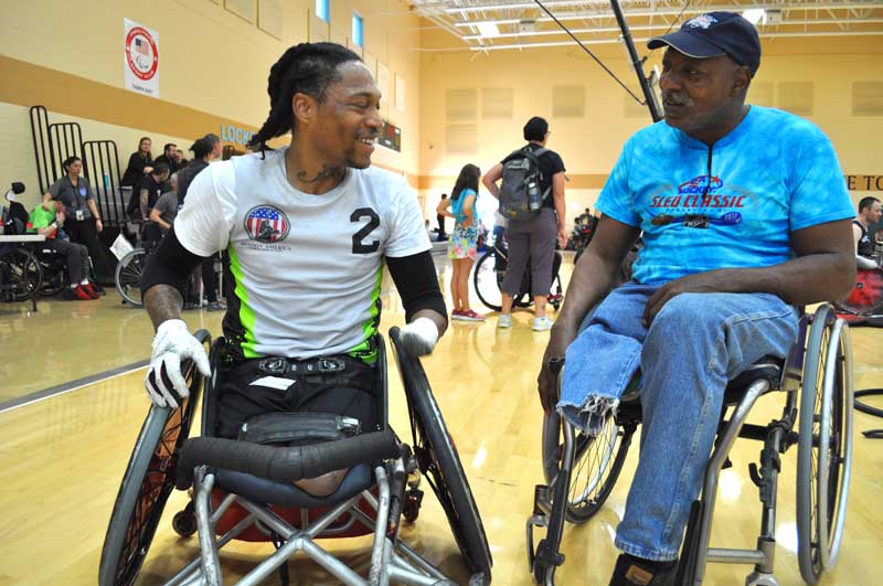 A wheelchair rugby player talking with a fan