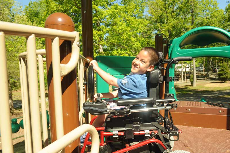 A child who uses a wheelchair enjoying an accessible playground