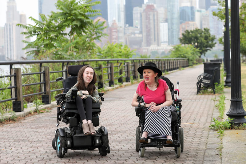 Two women using power wheelchairs